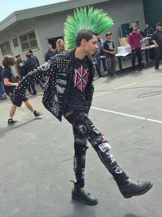 Person in punk rock attire with green mohawk standing on a concrete surface.